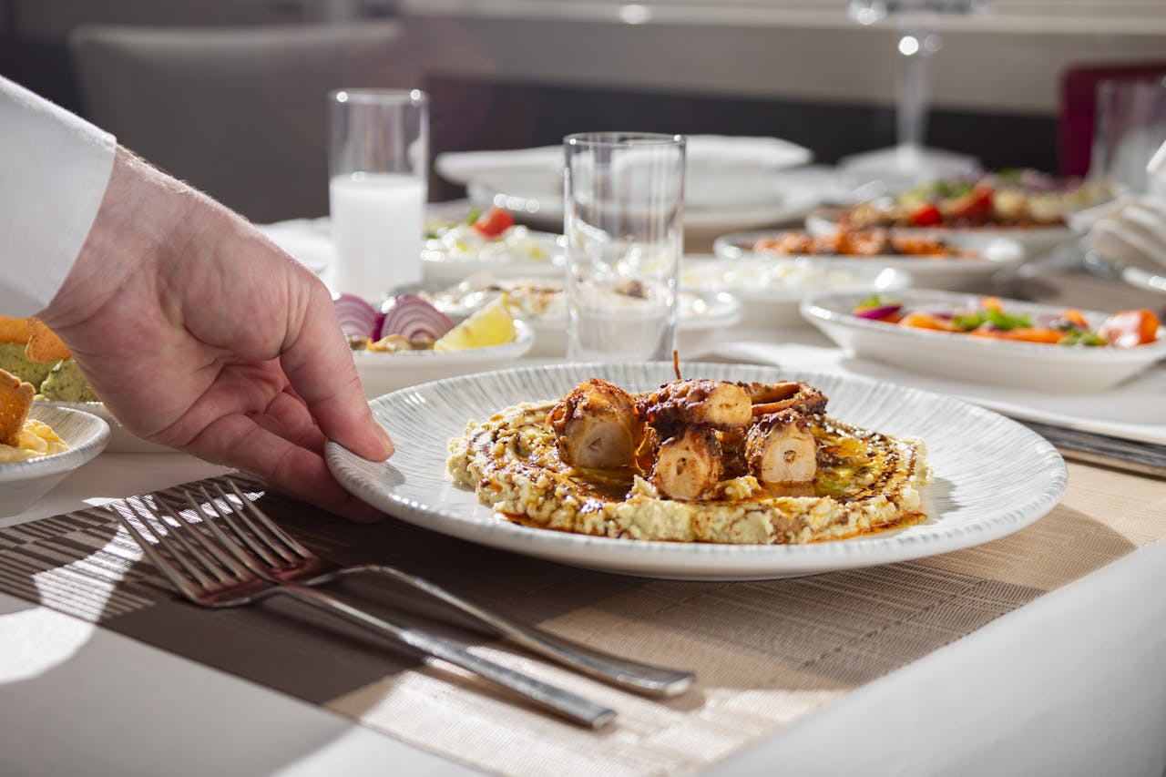 Close-up of a gourmet octopus dish being served at an elegant dining table.